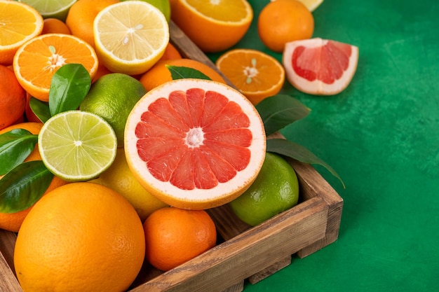 Different citrus fruits with leaves in a wooden box on a concrete background Healthy food Top view