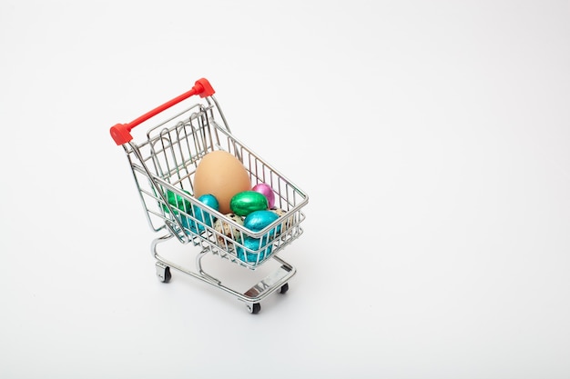 Different color and size eggs are in the grocery cart on the white background