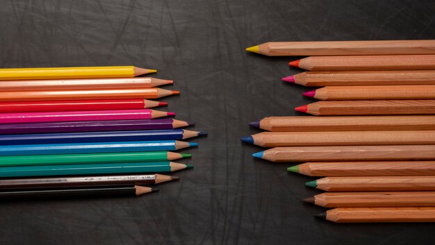 Different color wooden pencils on black chalkboard background