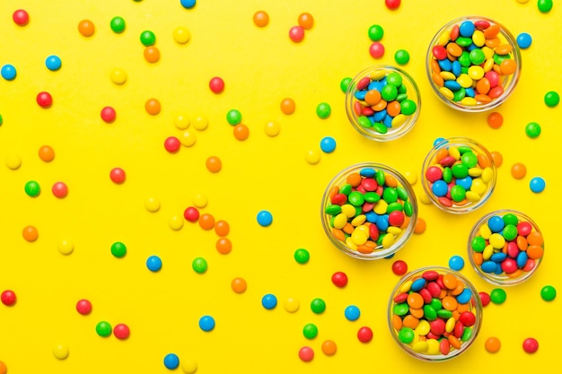 different colored round candy in bowl and jars Top view of large variety sweets and candies with copy space