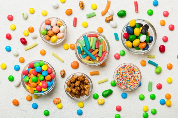 different colored round candy in bowl and jars Top view of large variety sweets and candies with copy space