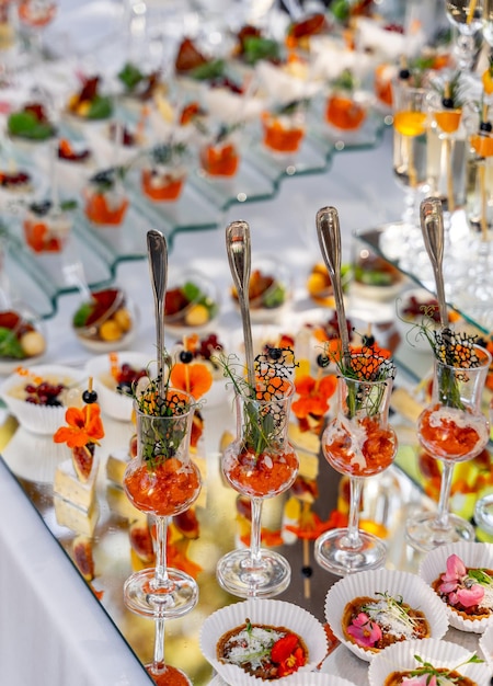 Different colorful appetizers standing at the party table. Fruits, vegetables and sea food products. Catering concept