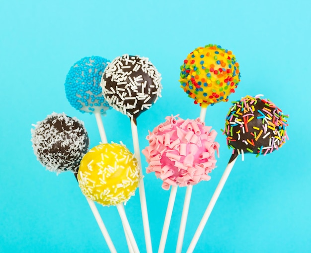 Different colorful cake pops on blue background