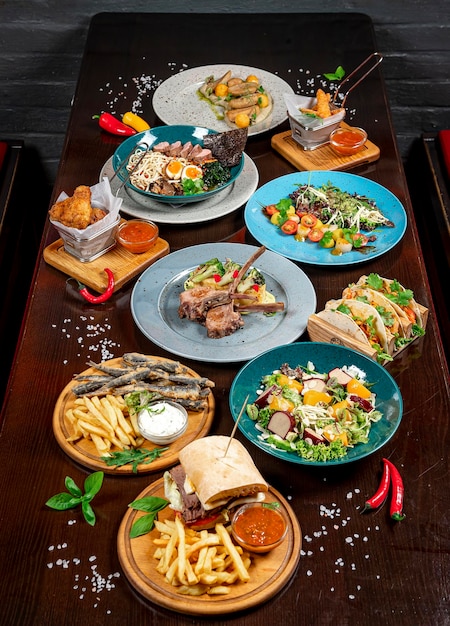 Different colorful meals on dark wooden table in the restaurant