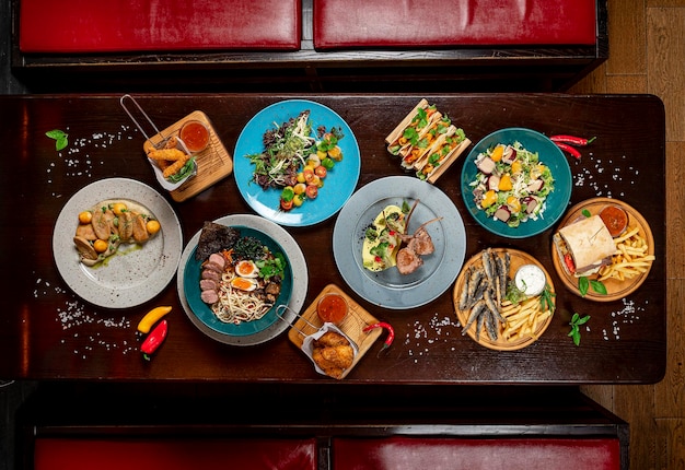 Different colorful meals on dark wooden table in the restaurant