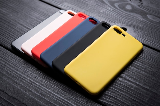 different colour phone cases on black woden background