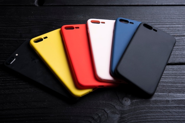 different colour phone cases on black woden background