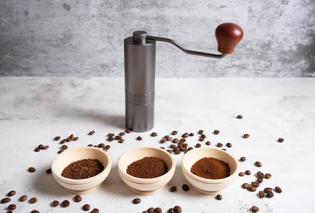 Different degrees of grinding of natural coffee next to a manual coffee grinder