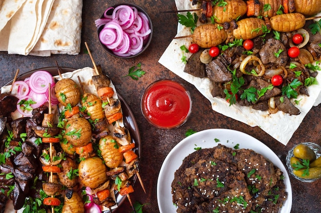 Different dishes of liver kebab Skewered liver whole vegetables and mushrooms on skewers