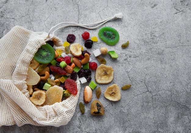 Photo different dried fruits and nuts in an eco bag on a gray concrete surface