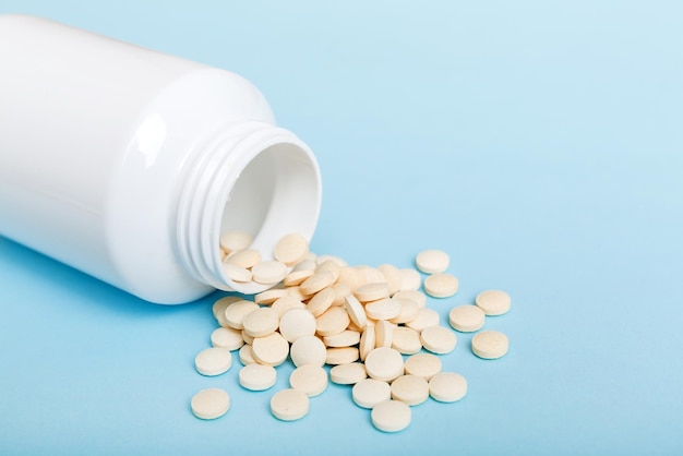 Different drugs and health supplement pills poured from a medicine bottle health care and medical top view on colored background