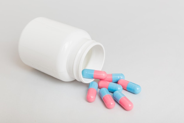 Different drugs and health supplement pills poured from a medicine bottle health care and medical top view on colored background