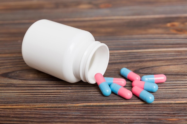 Different drugs and health supplement pills poured from a medicine bottle health care and medical top view on colored background