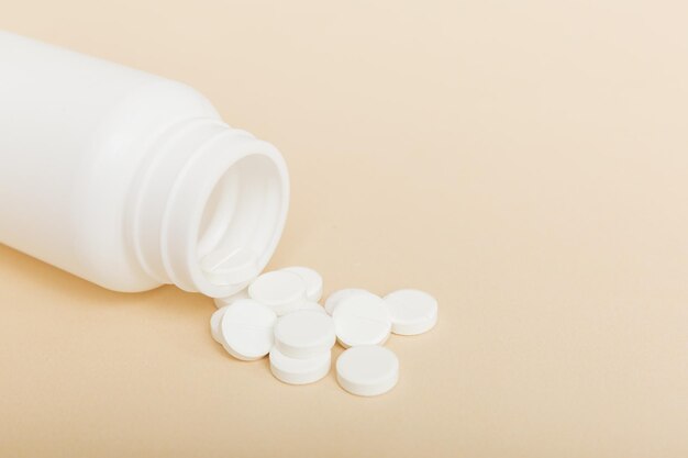 Different drugs and health supplement pills poured from a medicine bottle health care and medical top view on colored background