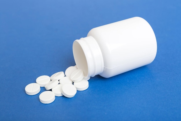 different drugs and health supplement pills poured from a medicine bottle health care and medical top view on colored background