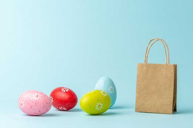 Different Easter eggs with shopping bag on blue background