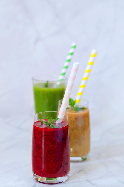 different fresh healthy smoothies in a glasses made of peach, banana and berries with mint. Drinks