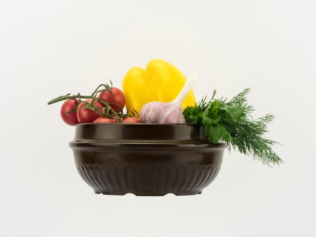 Different fresh vegetables in ceramic bowl on white background in horizontal perspective