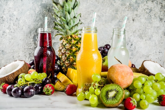 Different fruit juices smoothies concept, summer vitamins diet, with tropical fruits and berries on a light background,