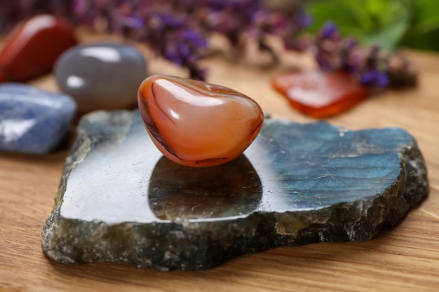 Different gemstones and healing herbs on wooden table closeup