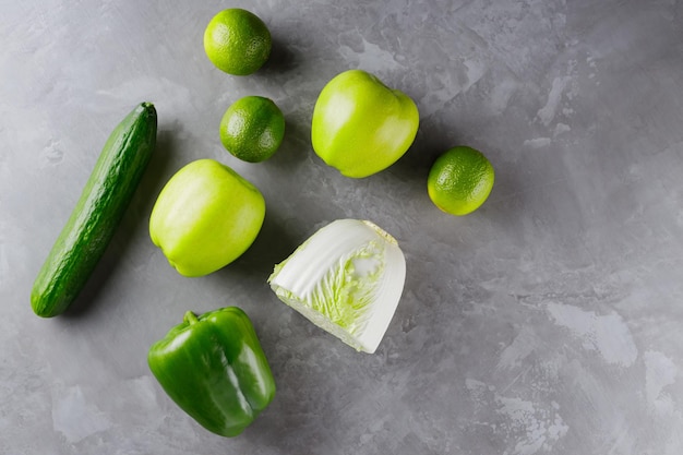 Different green vegetables and fruits on gray background. Healthy food concept. Top view. Copy space