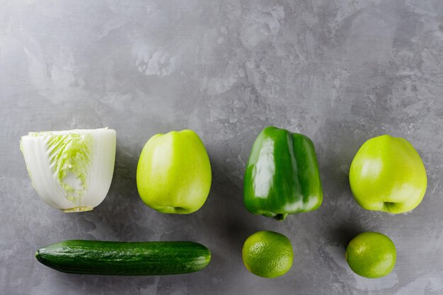 Different green vegetables and fruits on gray background. Healthy food concept. Top view. Copy space