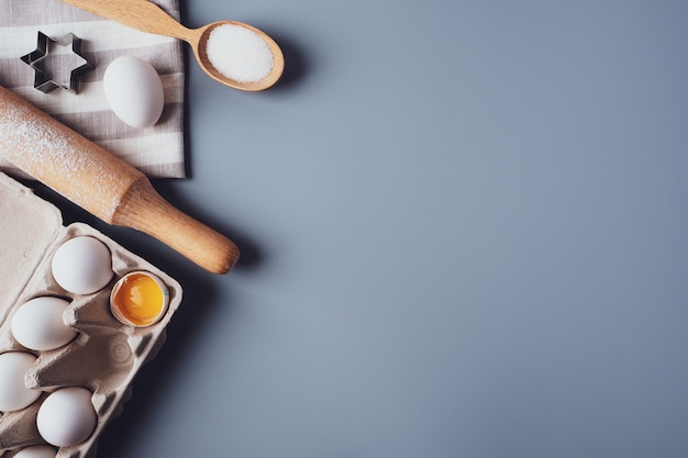 Different ingredients and kitchen utensils for making cookies or cupcakes, flat lay, copyspace.