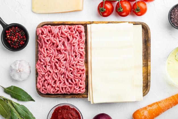 Different ingredients for lasagna on white stone background top view flat lay