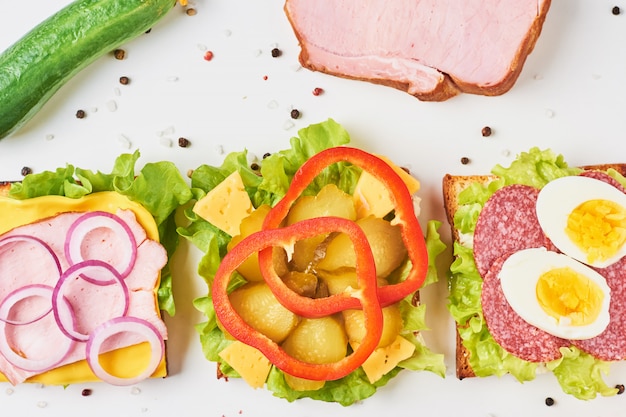 Different kind of sandwich and ingredients on a white background, top view