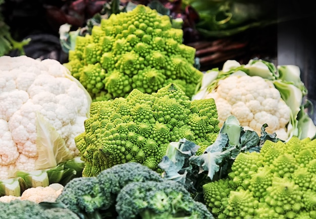 Different kinds of cabbage (Romanesco, broccoli, cauliflower) in a basket at market.