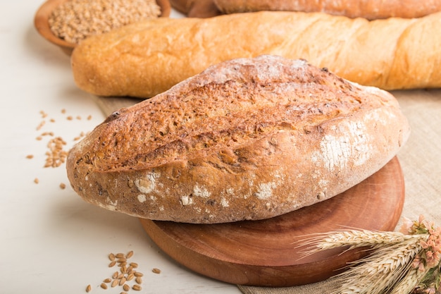 Different kinds of fresh baked bread on a white wooden surface. side view, selective focus.