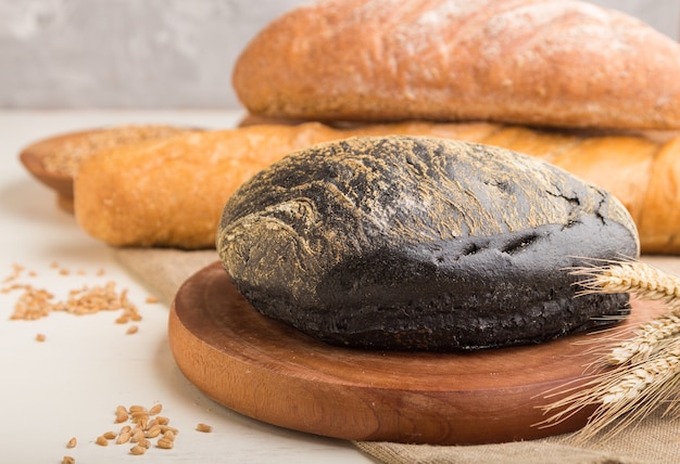 Different kinds of fresh baked bread on a white wooden surface