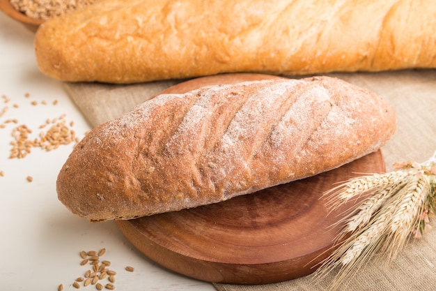 Different kinds of fresh baked bread on a white wooden wall. side view, selective focus.