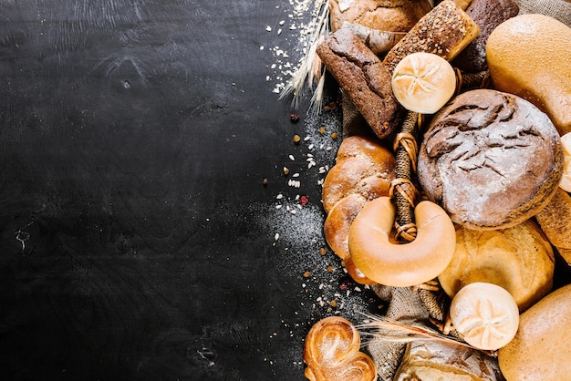 Different kinds of fresh bakery and breads on black wooden baclground Top view Copy space