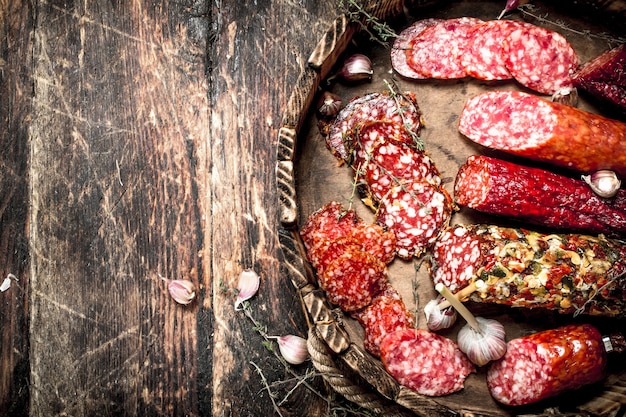 Different kinds of salami on the boards. On a wooden background.