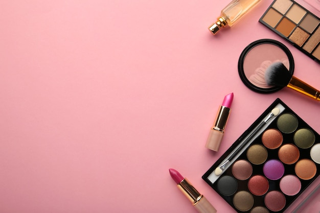 Different luxury makeup products on pink background, flat lay. Top view