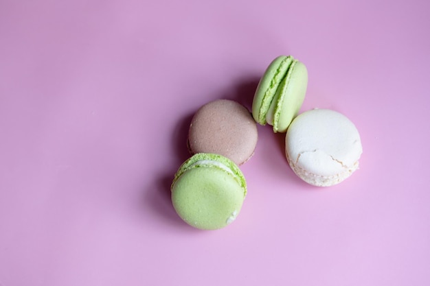 Different macaroons on a pink background copy space