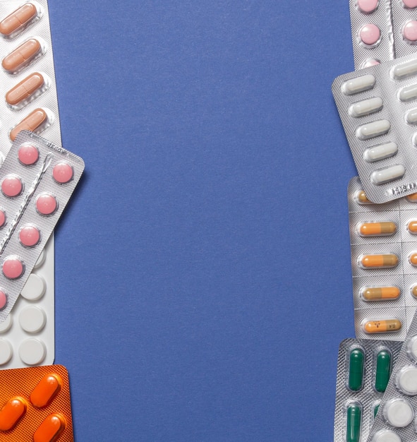 Different medicines, tablets, pills in blister pack, medications drugs on blue background. Close-up