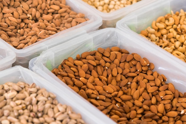 Different nuts Almonds cashews and pistachios in plastic containers on the counter