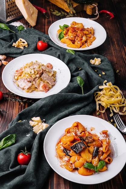 Different pasta dishes on wooden with fabric background