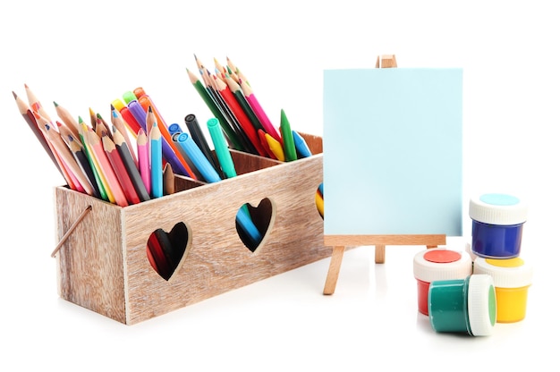 Different pencils in wooden crate paints and easel isolated on white