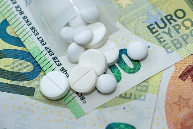 Different pills on euro bills as background. High cost of medicines