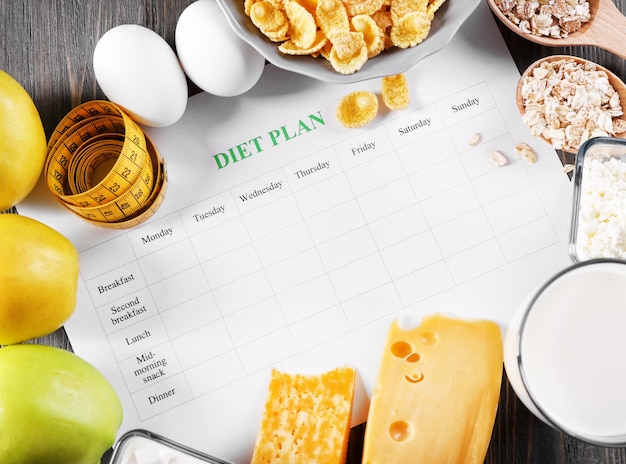 Different products diet plan and measuring tape on wooden background