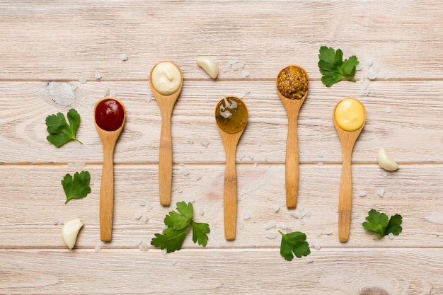 Different sauces in spoons on table background flat lay top view