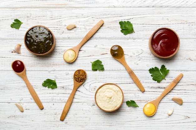 Different sauces in spoons on table background flat lay top view