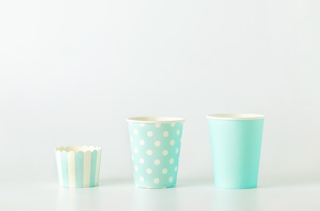 Different size of blue paper cup with white polka dot and striped pattern on white background