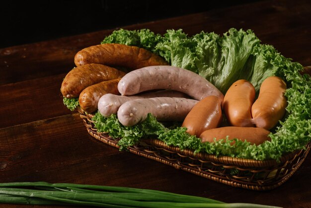 Different smoked sausages with vgetables and ingredients on wooden background