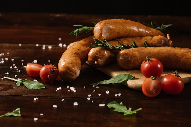 Different smoked sausages with vgetables and ingredients on wooden background