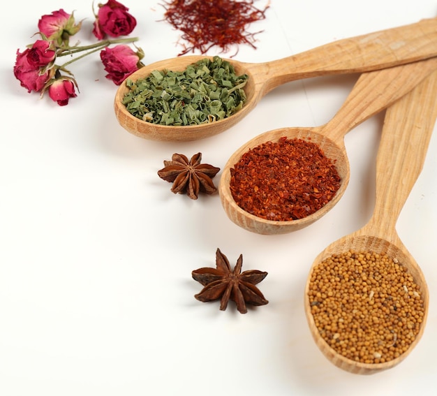 Different spices and herbs in wooden spoons isolated on white