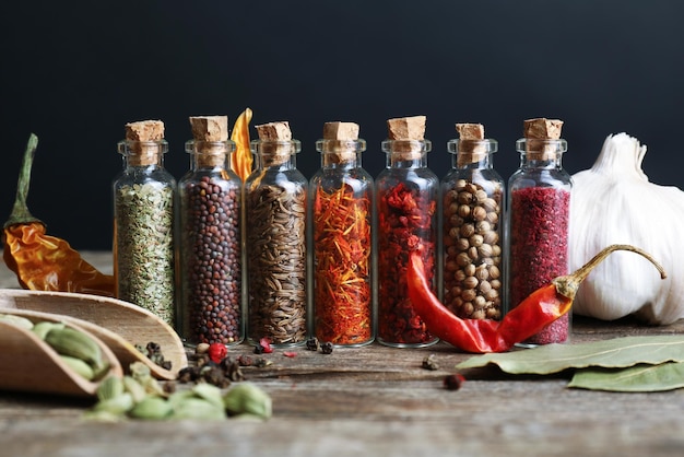 Different spices in small glass bottles on wooden table